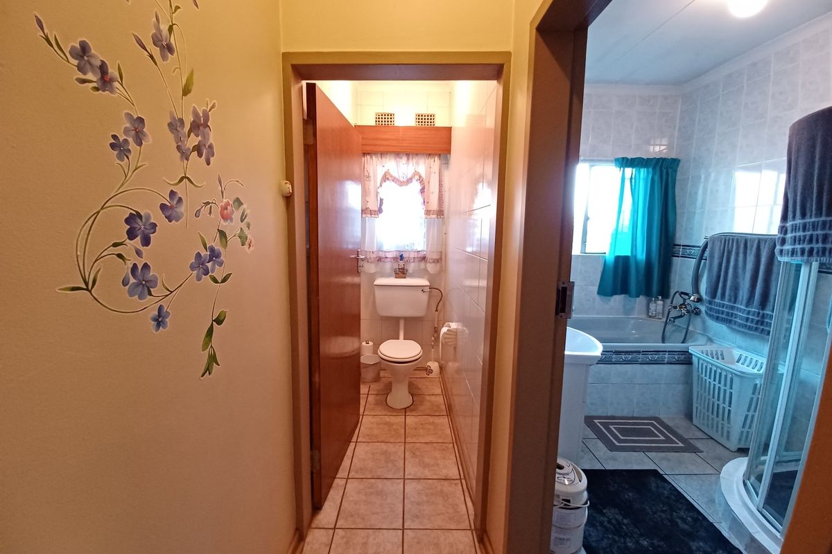 A functional bathroom featuring a separate toilet area, tiled walls and floors, a bathtub, and a shower enclosure.