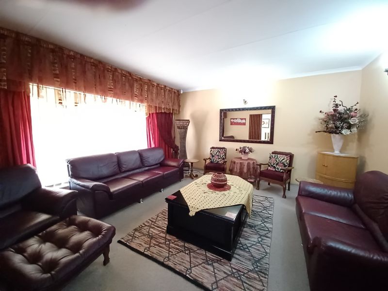 A spacious living room featuring neutral wall finishes, coved ceilings, and a large window allowing for ample natural light.