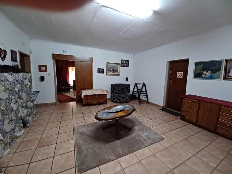 A spacious living area featuring tiled flooring and a sliding wooden door, with visible ceiling panel wear requiring maintenance.