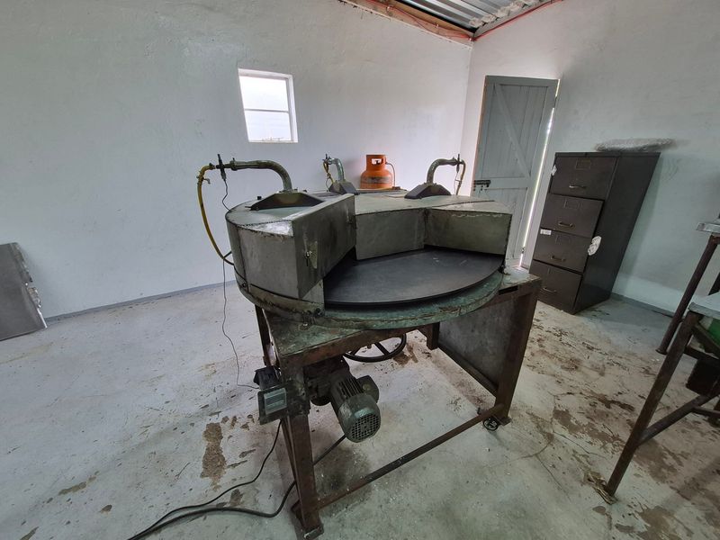 A utility space featuring industrial machinery, concrete flooring, and a timber door, suitable for workshop or storage use.