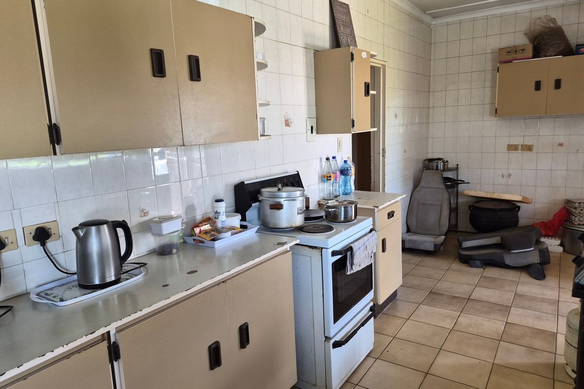 A dated kitchen featuring tiled walls, laminate countertops, and original built-in cabinetry, offering significant potential for modernization and renovation.
