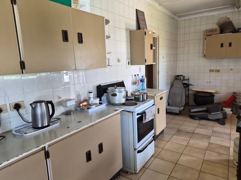 A dated kitchen featuring tiled walls, laminate countertops, and original built-in cabinetry, offering significant potential for modernization and renovation.