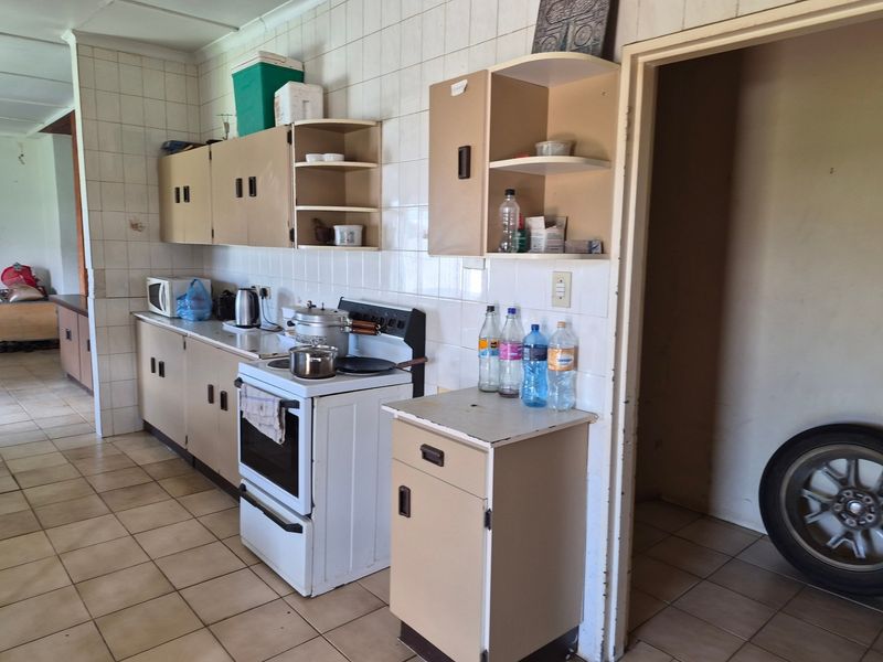 A functional kitchen featuring tiled walls and flooring with dated cabinetry and a freestanding stove, offering potential for modernization and cosmetic updates.