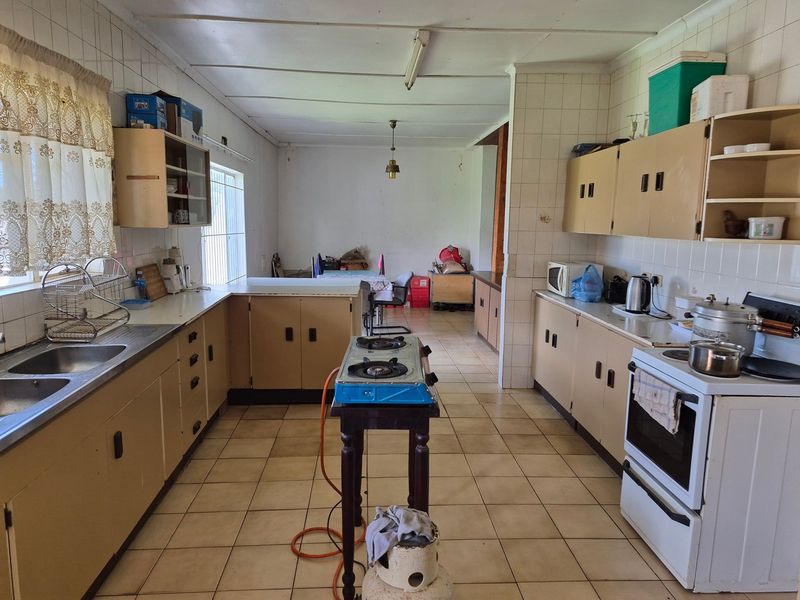 A spacious, dated kitchen featuring extensive built-in cabinetry, tiled splashbacks, and tiled flooring, offering significant potential for modernization and renovation.
