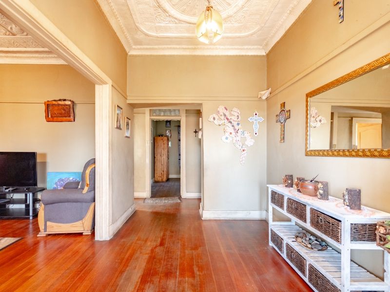 A spacious hallway featuring original pressed metal ceilings, decorative ceiling roses, and polished timber flooring, leading into the main living area.