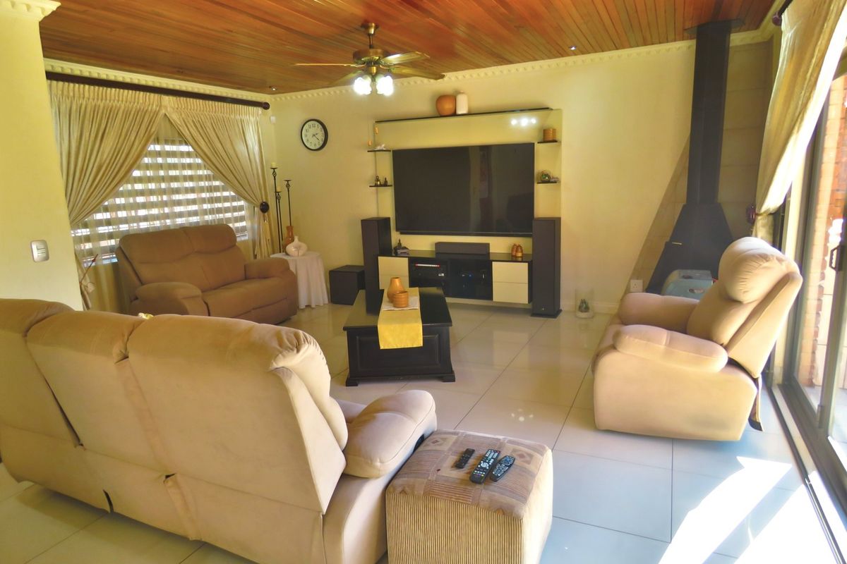 Spacious living room featuring a warm timber ceiling, tiled flooring, and a modern freestanding fireplace, creating a comfortable and inviting atmosphere.