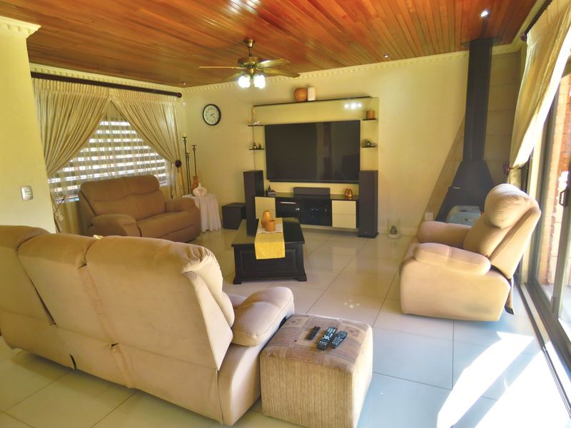 Spacious living room featuring a warm timber ceiling, tiled flooring, and a modern freestanding fireplace, creating a comfortable and inviting atmosphere.