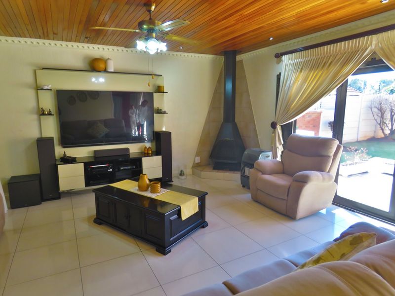 Spacious living room featuring a timber-clad ceiling, tiled flooring, a modern freestanding fireplace, and direct access to the outdoor area via sliding glass doors.