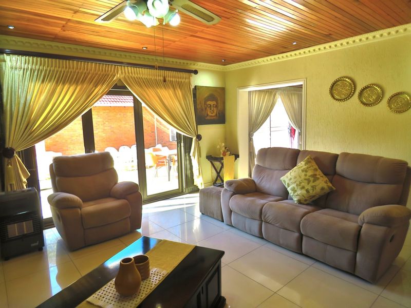 A comfortable living room featuring a warm timber ceiling, tiled flooring, and large sliding glass doors providing direct access to the outdoor patio area.