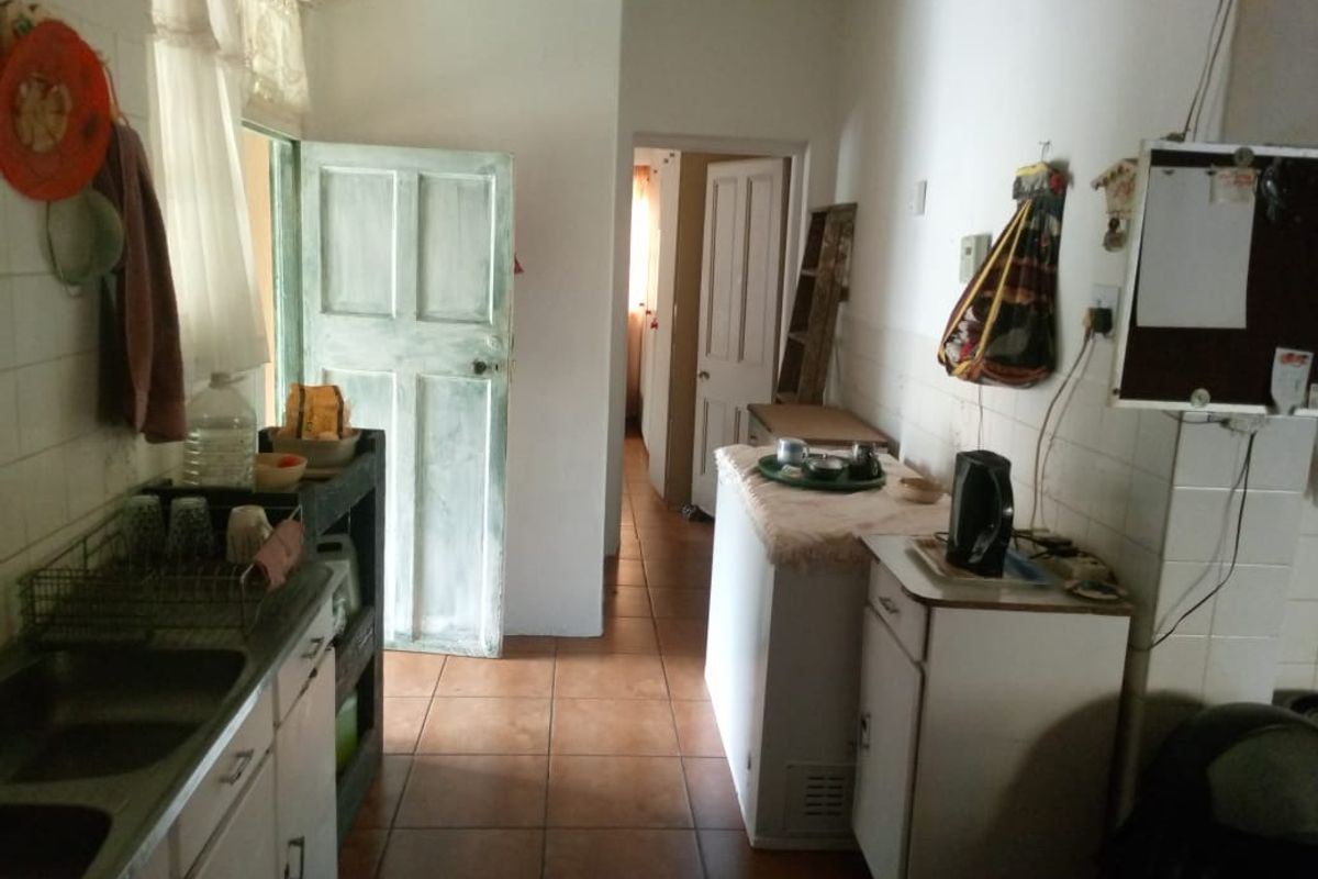 A functional kitchen area featuring tiled flooring, built-in cabinetry, and a stainless steel sink, requiring cosmetic updates to modernize the space.