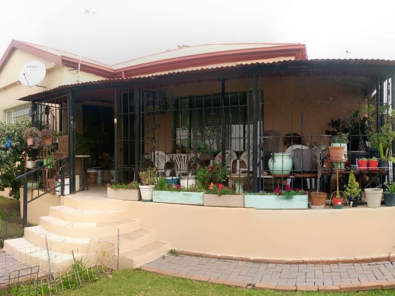 Front elevation of a house featuring a covered patio area with security bars, concrete steps, and a paved walkway.