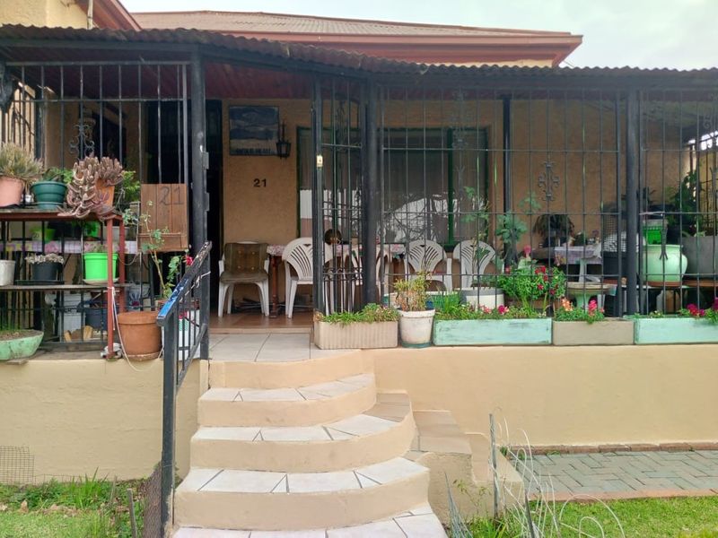 Front entrance of the house featuring a covered patio area with security gates and tiled steps leading up to the main door.