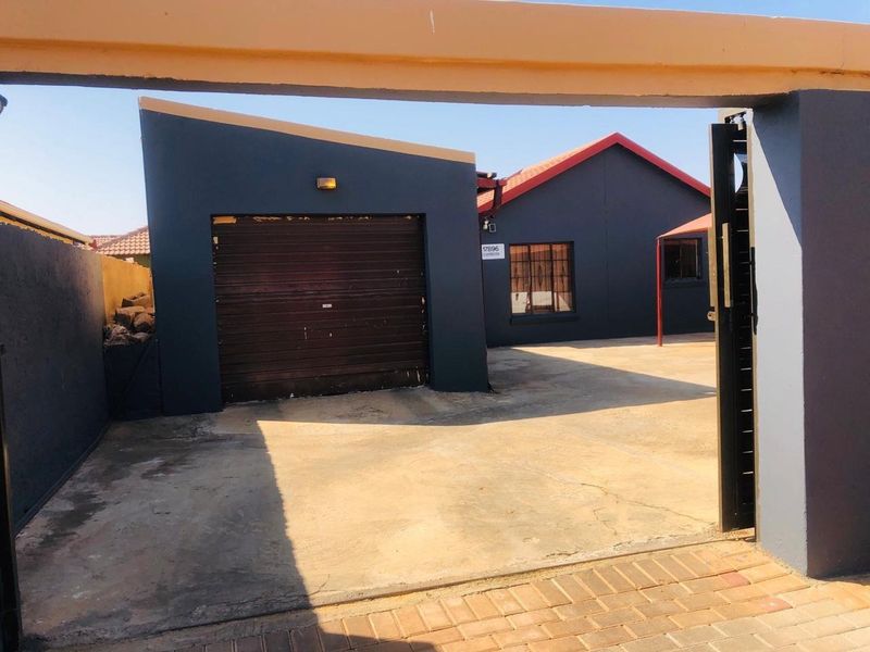 Front view of a residential property featuring a single garage, concrete driveway, and secure perimeter walling.