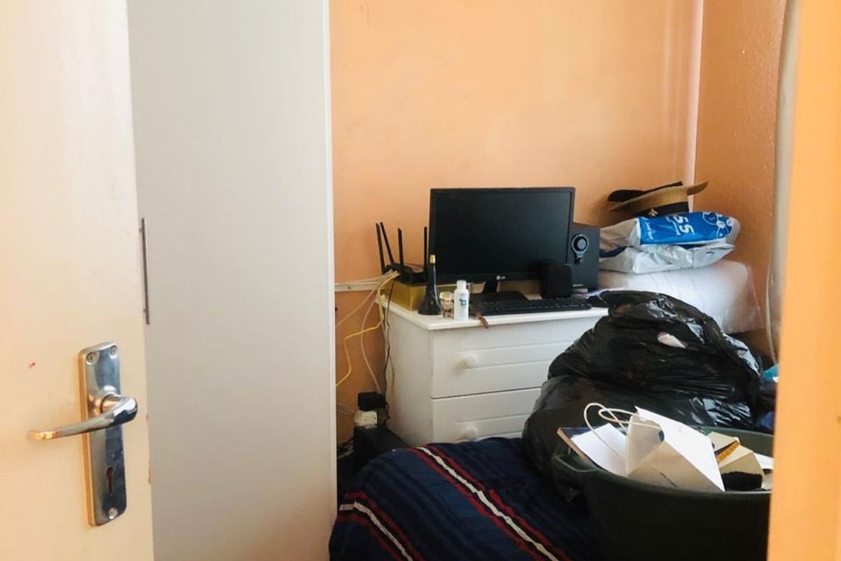A compact bedroom featuring a built-in wardrobe, vinyl flooring, and painted walls, currently used as a multi-purpose space.