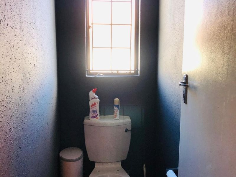 A compact, dark-painted toilet room featuring a standard white toilet suite and a small window for natural light.