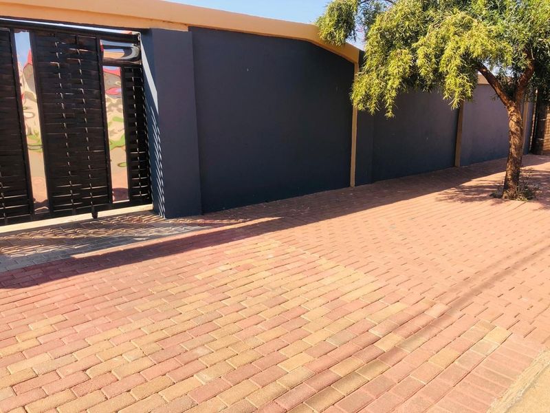 A view of the property's front boundary wall, sliding gate, and paved driveway area.