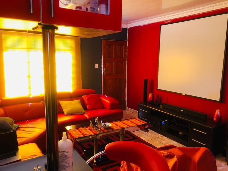 A dedicated cinema room featuring a large wall-mounted projector screen, tiled flooring, and decorative coved ceiling details.
