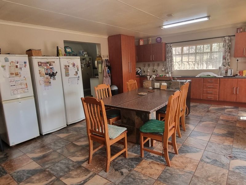 Open-plan kitchen and dining area featuring wooden cabinetry, tiled flooring, and built-in oven, offering a functional space with potential for modern updates.