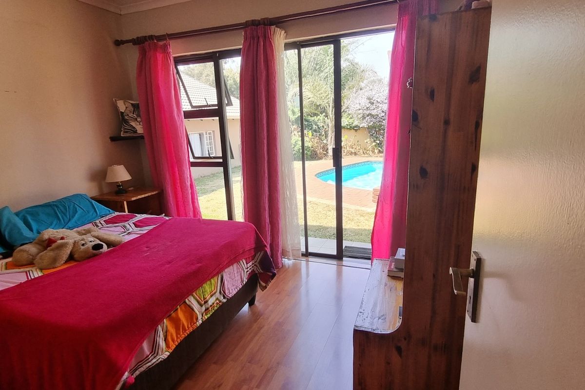 Bedroom featuring laminate flooring and a sliding glass door providing direct access to the garden and pool area.