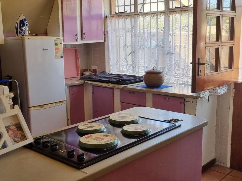 A functional kitchen featuring built-in cabinetry, an electric hob, and an integrated oven, with direct access to the exterior through a wooden door.