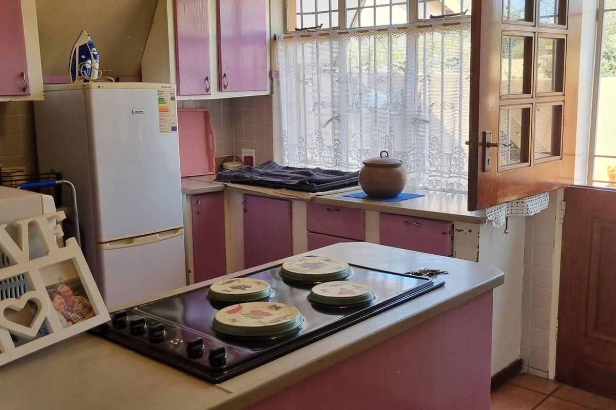 A functional kitchen featuring built-in cabinetry, an electric hob, and an integrated oven, with direct access to the exterior through a wooden door.