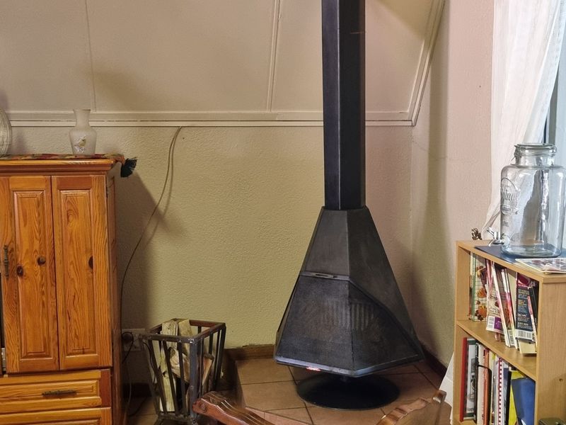 A living room area featuring a prominent black metal freestanding fireplace set on a tiled hearth against a sloped wall.