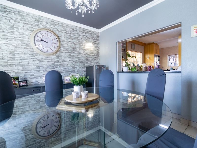 Dining room featuring a stone veneer accent wall, crown molding, and a convenient pass-through window connecting to the kitchen area.