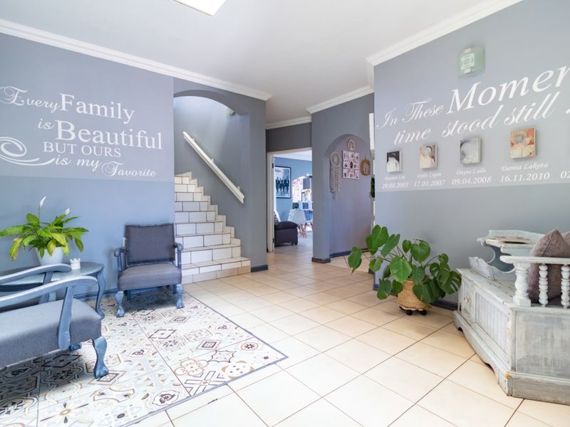 Spacious entrance hall featuring tiled flooring, an arched staircase, and decorative wall finishes, providing a welcoming transition into the home.