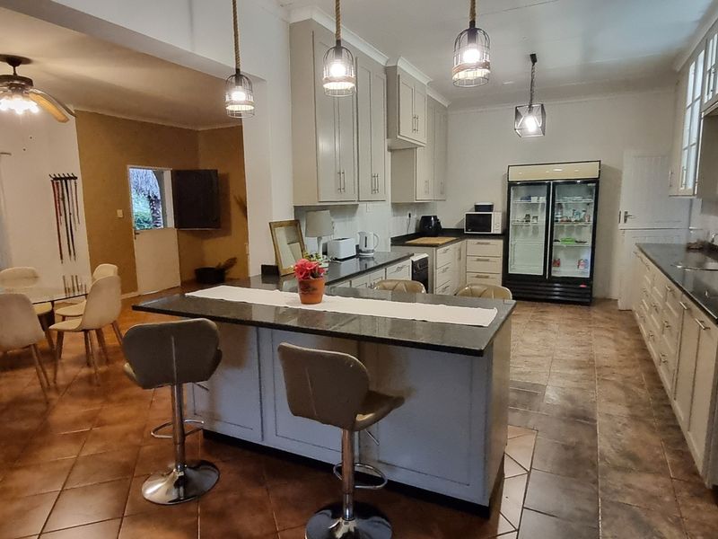 Spacious open-plan kitchen and dining area featuring a central island, granite countertops, ample cabinetry, and tiled flooring throughout.