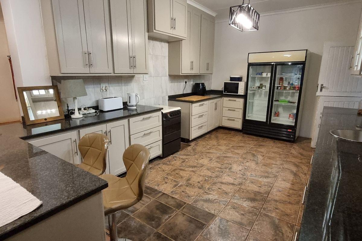 Spacious kitchen featuring granite countertops, ample built-in cabinetry, tiled flooring, and a functional layout with a breakfast bar area.