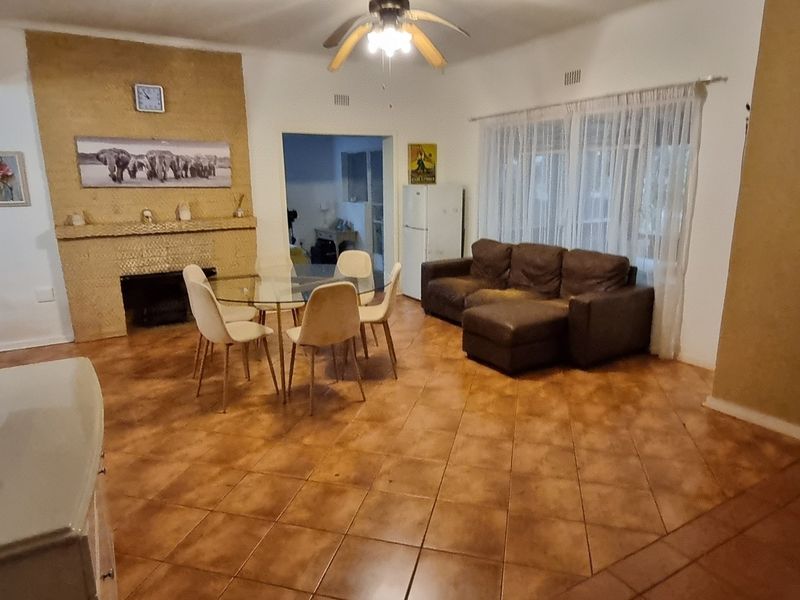 Spacious living area featuring tiled flooring, a central fireplace with a built-in mantelpiece, and a ceiling fan, offering a functional layout for family living.
