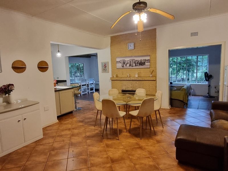 Open-plan living and dining area featuring a central brick fireplace, tiled flooring, and direct access to adjacent kitchen and living spaces.