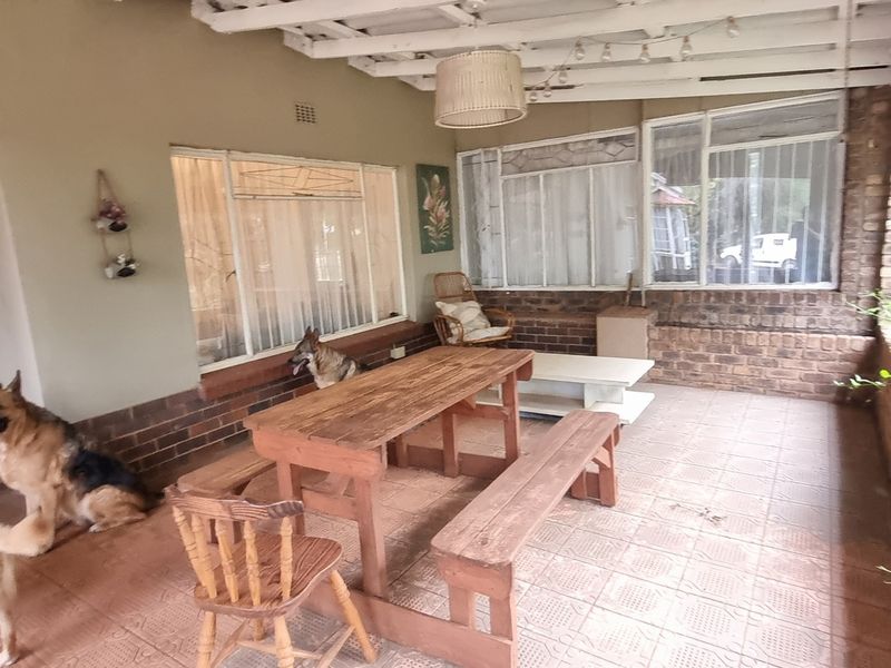 A covered outdoor patio area featuring facebrick walls, tiled flooring, and exposed timber ceiling beams, providing a functional space for outdoor relaxation.