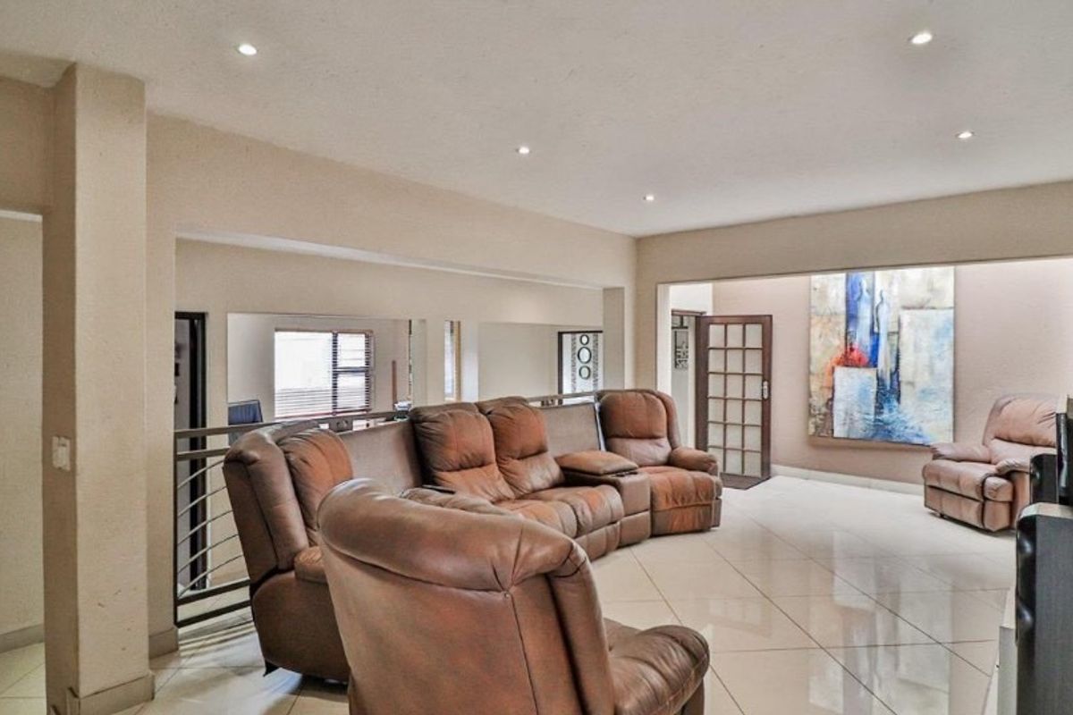 Spacious living area featuring neutral tiled flooring, recessed downlighting, and a metal balustrade overlooking the lower level.