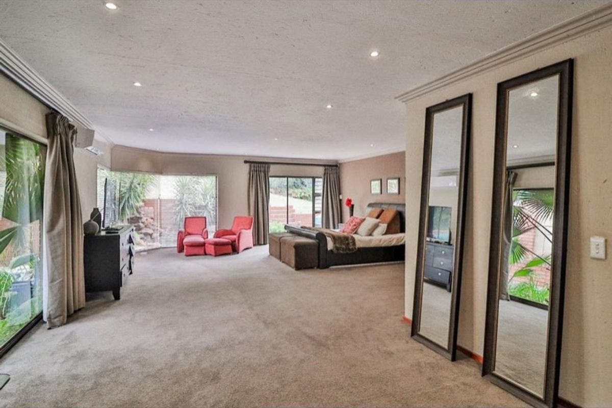 Spacious bedroom featuring neutral carpeting, recessed downlighting, and large sliding glass doors providing natural light and garden access.