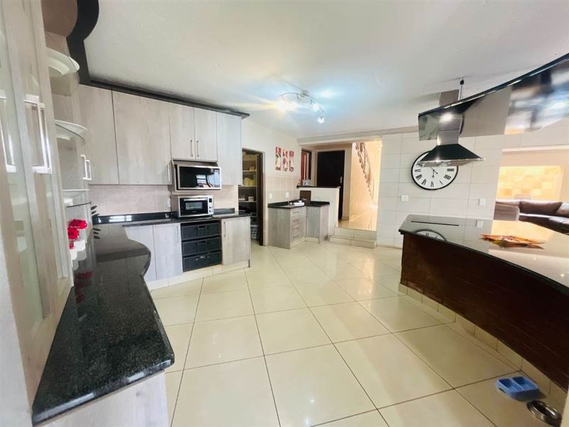Spacious kitchen featuring modern cabinetry, granite countertops, built-in appliances, and a large central island, seamlessly flowing into the adjacent living area.