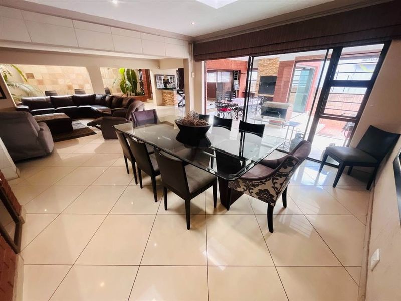 Spacious open-plan living and dining area featuring large format floor tiles, recessed lighting, and seamless access to the outdoor patio through sliding glass doors.