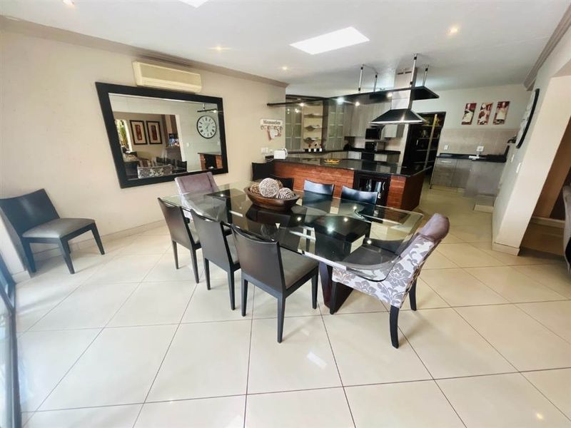 Spacious open-plan dining and kitchen area featuring tiled floors, a central kitchen island, modern cabinetry, and a skylight for natural illumination.