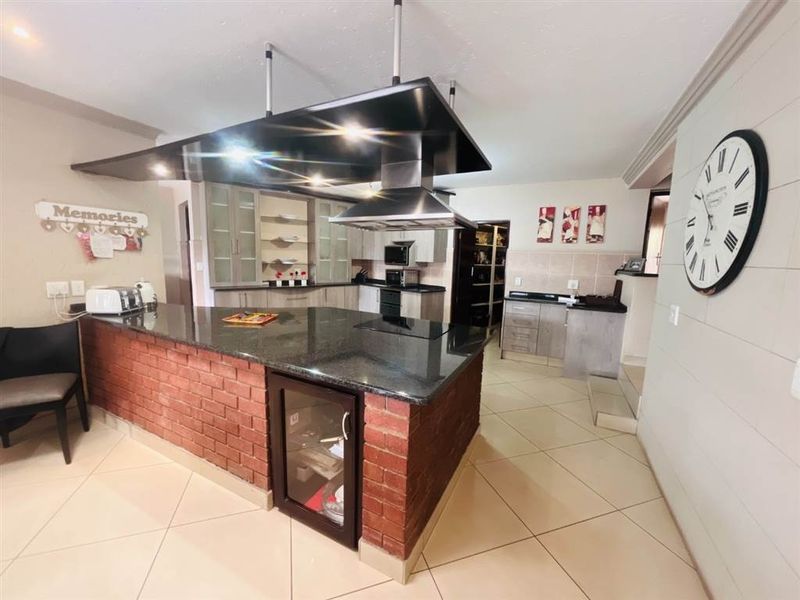 Spacious kitchen featuring a large central island with a brick base, granite countertops, integrated extractor fan, and ample built-in cabinetry.