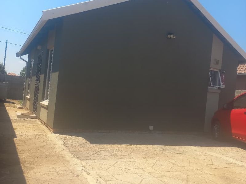 Side view of the property showing the exterior wall, gabled roofline, and concrete driveway area.