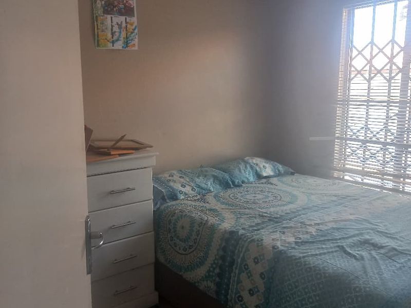 A standard bedroom featuring tiled flooring and a window fitted with a security gate.
