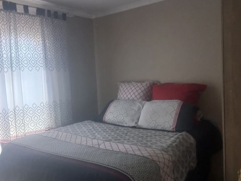 A standard bedroom featuring tiled flooring and neutral wall tones, providing a functional space for rest.