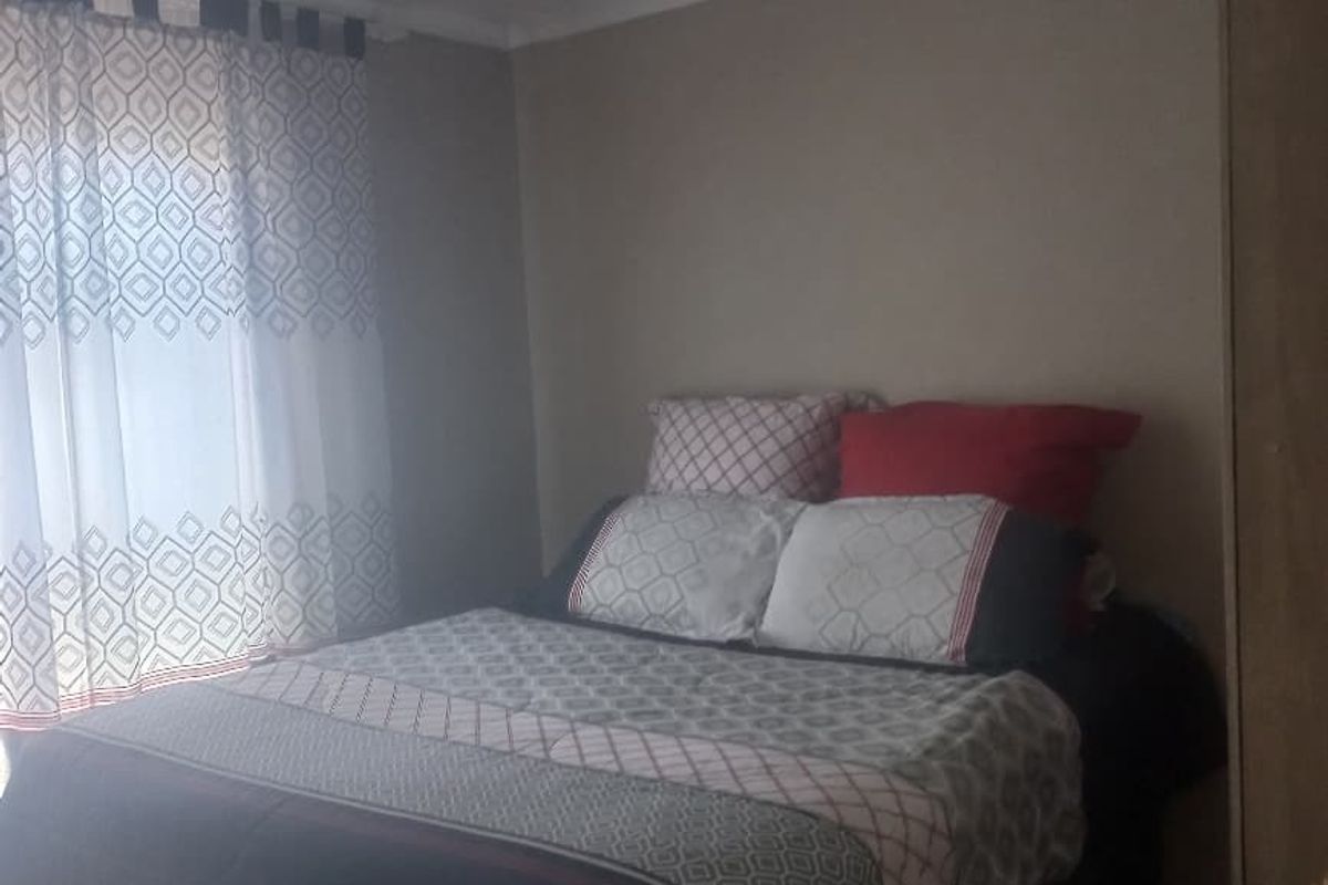 A standard bedroom featuring tiled flooring and neutral wall tones, providing a functional space for rest.
