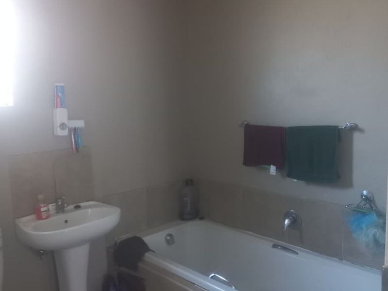 A functional bathroom featuring a pedestal basin and a built-in bathtub with tiled splashback surrounds.