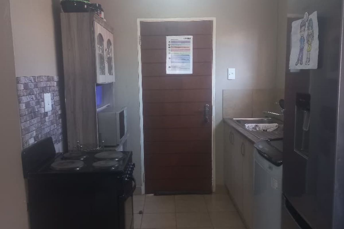A functional kitchen area featuring tiled flooring, built-in cabinetry, and a freestanding electric stove, providing a practical space for meal preparation.