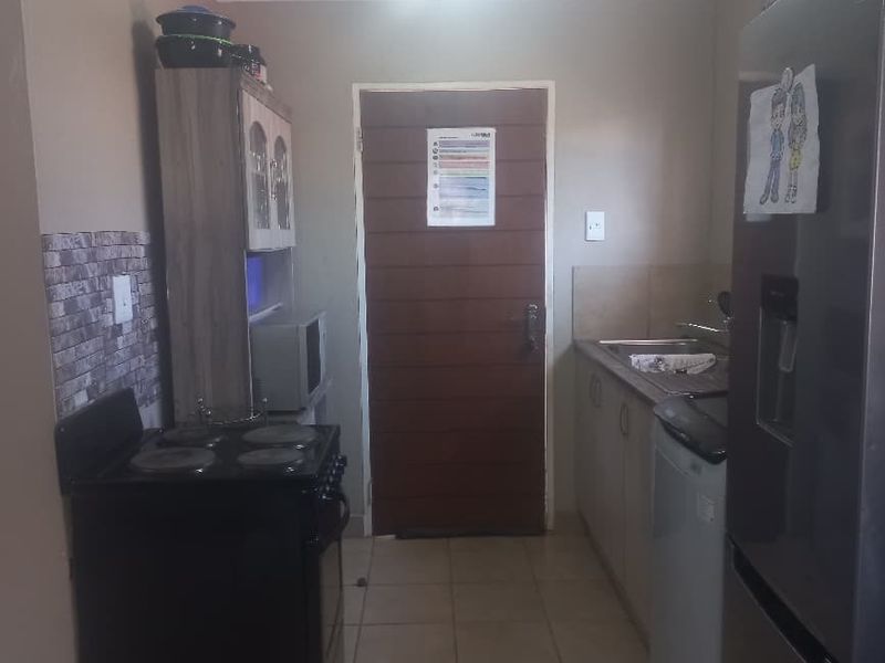 A functional kitchen area featuring tiled flooring, built-in cabinetry, and a freestanding electric stove, providing a practical space for meal preparation.