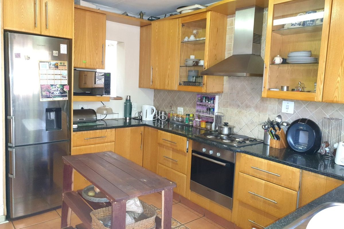 A functional kitchen featuring wooden cabinetry, granite countertops, a built-in oven, and a stainless steel extractor fan with a tiled backsplash.