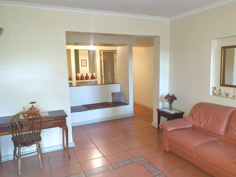 A living area featuring terracotta tiled flooring, a built-in bench seat within a recessed alcove, and a coved ceiling.