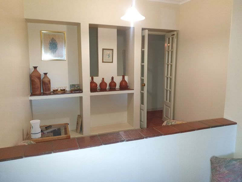 A living area featuring built-in wall niches, a terracotta-tiled half-wall partition, and classic french doors leading to an adjacent space.