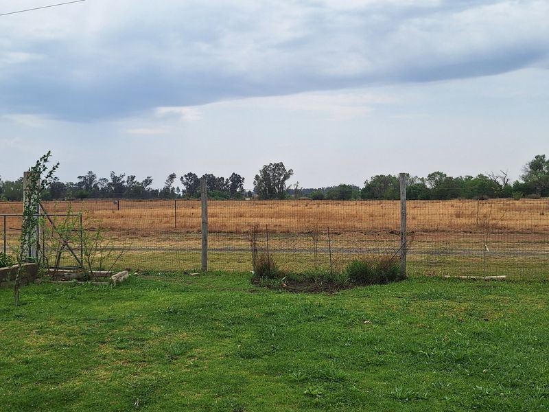 A view of the open field and surrounding landscape from the property, featuring wire mesh fencing and a utility pole.